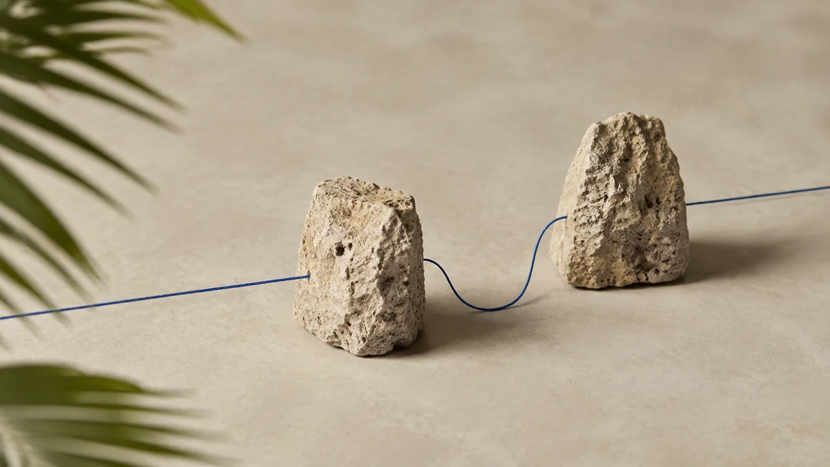 Internet costs: a taut blue thread finding a clean path around two limestone blocks